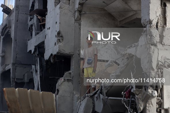 Palestinians are standing on the rubble of Abdullah Azzam Mosque, destroyed in Israeli bombardment in Nuseirat, central Gaza Strip, on July...