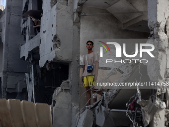 Palestinians are standing on the rubble of Abdullah Azzam Mosque, destroyed in Israeli bombardment in Nuseirat, central Gaza Strip, on July...