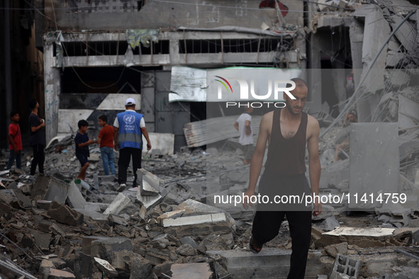 Palestinians are standing on the rubble of Abdullah Azzam Mosque, destroyed in Israeli bombardment in Nuseirat, central Gaza Strip, on July...