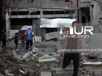 Palestinians are standing on the rubble of Abdullah Azzam Mosque, destroyed in Israeli bombardment in Nuseirat, central Gaza Strip, on July...