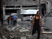 Palestinians are standing on the rubble of Abdullah Azzam Mosque, destroyed in Israeli bombardment in Nuseirat, central Gaza Strip, on July...