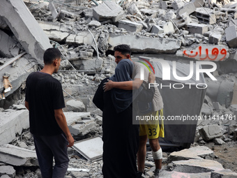 Palestinians are standing on the rubble of Abdullah Azzam Mosque, destroyed in Israeli bombardment in Nuseirat, central Gaza Strip, on July...