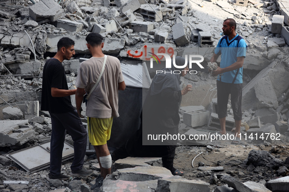 Palestinians are standing on the rubble of Abdullah Azzam Mosque, destroyed in Israeli bombardment in Nuseirat, central Gaza Strip, on July...