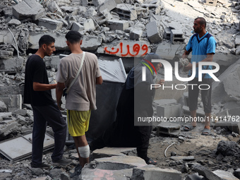 Palestinians are standing on the rubble of Abdullah Azzam Mosque, destroyed in Israeli bombardment in Nuseirat, central Gaza Strip, on July...