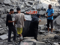 Palestinians are standing on the rubble of Abdullah Azzam Mosque, destroyed in Israeli bombardment in Nuseirat, central Gaza Strip, on July...