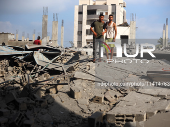 Palestinians are standing on the rubble of Abdullah Azzam Mosque, destroyed in Israeli bombardment in Nuseirat, central Gaza Strip, on July...