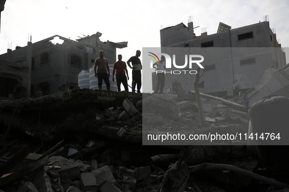 Palestinians are standing on the rubble of Abdullah Azzam Mosque, destroyed in Israeli bombardment in Nuseirat, central Gaza Strip, on July...