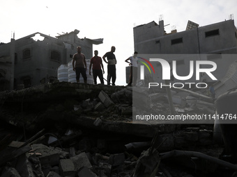 Palestinians are standing on the rubble of Abdullah Azzam Mosque, destroyed in Israeli bombardment in Nuseirat, central Gaza Strip, on July...