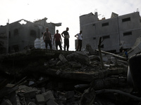 Palestinians are standing on the rubble of Abdullah Azzam Mosque, destroyed in Israeli bombardment in Nuseirat, central Gaza Strip, on July...