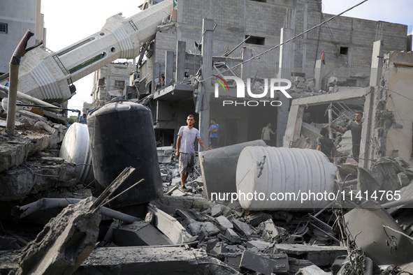 Palestinians are standing on the rubble of Abdullah Azzam Mosque, destroyed in Israeli bombardment in Nuseirat, central Gaza Strip, on July...