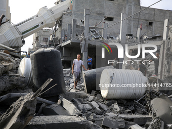 Palestinians are standing on the rubble of Abdullah Azzam Mosque, destroyed in Israeli bombardment in Nuseirat, central Gaza Strip, on July...