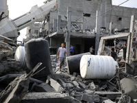 Palestinians are standing on the rubble of Abdullah Azzam Mosque, destroyed in Israeli bombardment in Nuseirat, central Gaza Strip, on July...