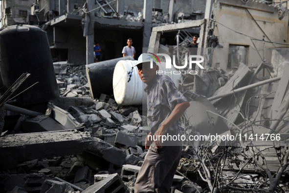 Palestinians are standing on the rubble of Abdullah Azzam Mosque, destroyed in Israeli bombardment in Nuseirat, central Gaza Strip, on July...