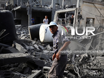 Palestinians are standing on the rubble of Abdullah Azzam Mosque, destroyed in Israeli bombardment in Nuseirat, central Gaza Strip, on July...