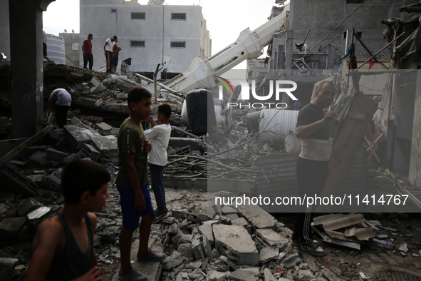 Palestinians are standing on the rubble of Abdullah Azzam Mosque, destroyed in Israeli bombardment in Nuseirat, central Gaza Strip, on July...