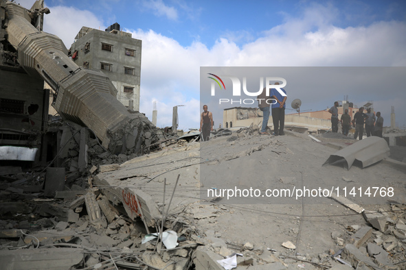 Palestinians are standing on the rubble of Abdullah Azzam Mosque, destroyed in Israeli bombardment in Nuseirat, central Gaza Strip, on July...