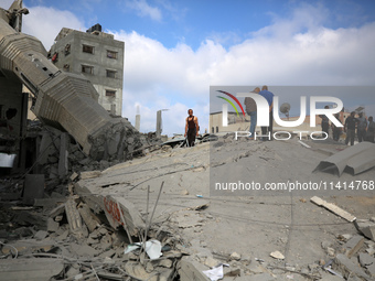 Palestinians are standing on the rubble of Abdullah Azzam Mosque, destroyed in Israeli bombardment in Nuseirat, central Gaza Strip, on July...