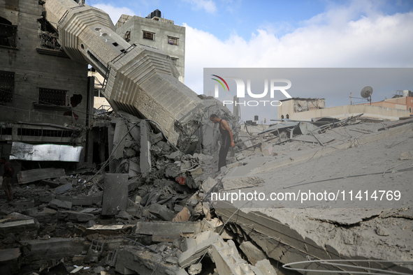 Palestinians are standing on the rubble of Abdullah Azzam Mosque, destroyed in Israeli bombardment in Nuseirat, central Gaza Strip, on July...