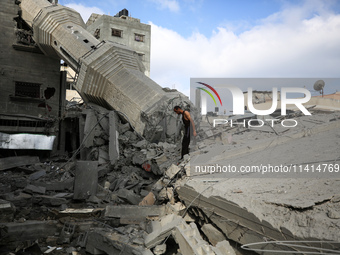 Palestinians are standing on the rubble of Abdullah Azzam Mosque, destroyed in Israeli bombardment in Nuseirat, central Gaza Strip, on July...