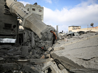 Palestinians are standing on the rubble of Abdullah Azzam Mosque, destroyed in Israeli bombardment in Nuseirat, central Gaza Strip, on July...