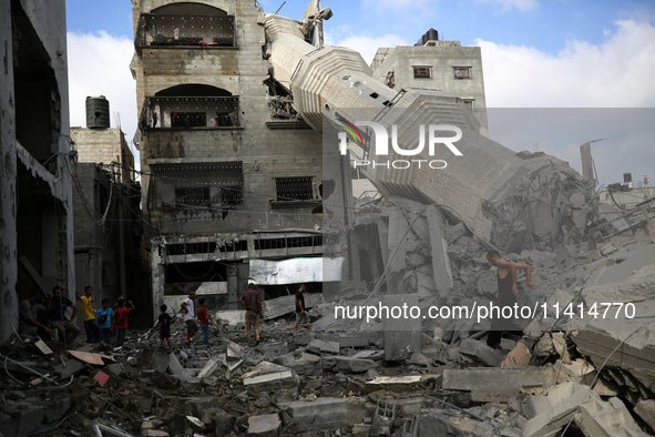 Palestinians are standing on the rubble of Abdullah Azzam Mosque, destroyed in Israeli bombardment in Nuseirat, central Gaza Strip, on July...