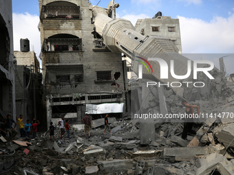 Palestinians are standing on the rubble of Abdullah Azzam Mosque, destroyed in Israeli bombardment in Nuseirat, central Gaza Strip, on July...