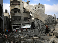 Palestinians are standing on the rubble of Abdullah Azzam Mosque, destroyed in Israeli bombardment in Nuseirat, central Gaza Strip, on July...