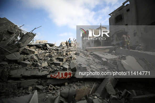 Palestinians are standing on the rubble of Abdullah Azzam Mosque, destroyed in Israeli bombardment in Nuseirat, central Gaza Strip, on July...