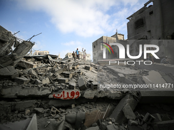 Palestinians are standing on the rubble of Abdullah Azzam Mosque, destroyed in Israeli bombardment in Nuseirat, central Gaza Strip, on July...