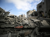 Palestinians are standing on the rubble of Abdullah Azzam Mosque, destroyed in Israeli bombardment in Nuseirat, central Gaza Strip, on July...