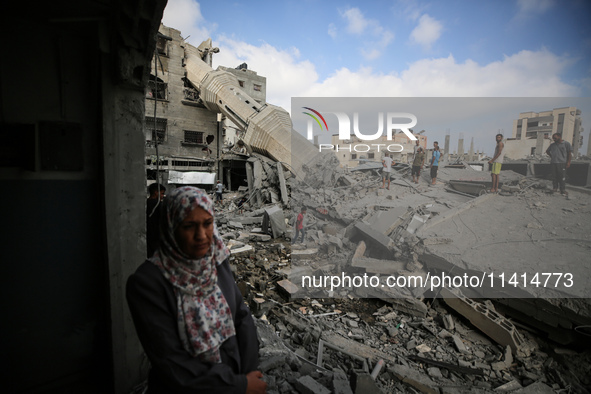 Palestinians are standing on the rubble of Abdullah Azzam Mosque, destroyed in Israeli bombardment in Nuseirat, central Gaza Strip, on July...