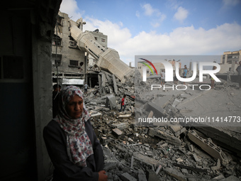 Palestinians are standing on the rubble of Abdullah Azzam Mosque, destroyed in Israeli bombardment in Nuseirat, central Gaza Strip, on July...