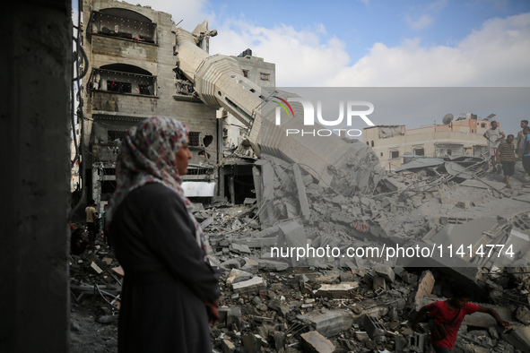 Palestinians are standing on the rubble of Abdullah Azzam Mosque, destroyed in Israeli bombardment in Nuseirat, central Gaza Strip, on July...