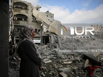 Palestinians are standing on the rubble of Abdullah Azzam Mosque, destroyed in Israeli bombardment in Nuseirat, central Gaza Strip, on July...