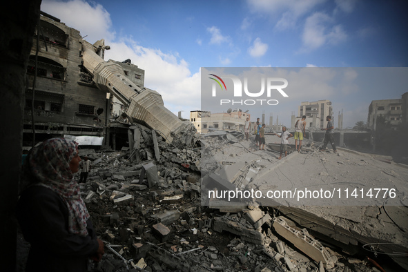 Palestinians are standing on the rubble of Abdullah Azzam Mosque, destroyed in Israeli bombardment in Nuseirat, central Gaza Strip, on July...