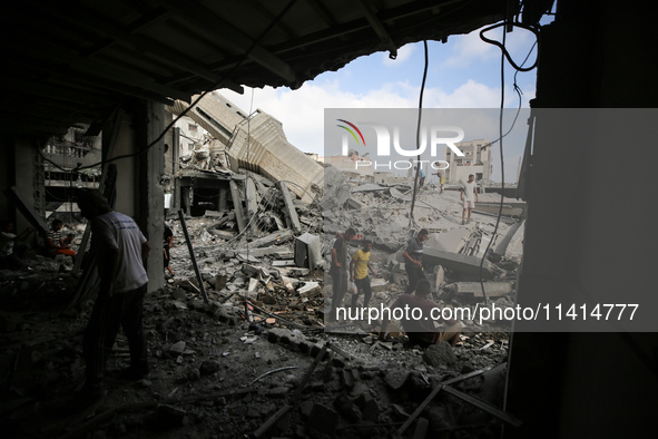 Palestinians are standing on the rubble of Abdullah Azzam Mosque, destroyed in Israeli bombardment in Nuseirat, central Gaza Strip, on July...