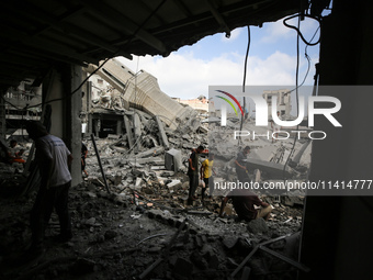 Palestinians are standing on the rubble of Abdullah Azzam Mosque, destroyed in Israeli bombardment in Nuseirat, central Gaza Strip, on July...