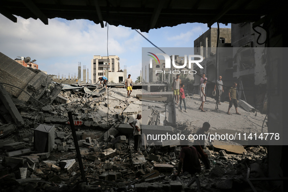 Palestinians are standing on the rubble of Abdullah Azzam Mosque, destroyed in Israeli bombardment in Nuseirat, central Gaza Strip, on July...