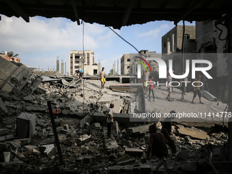 Palestinians are standing on the rubble of Abdullah Azzam Mosque, destroyed in Israeli bombardment in Nuseirat, central Gaza Strip, on July...