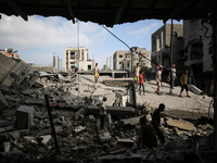 Palestinians are standing on the rubble of Abdullah Azzam Mosque, destroyed in Israeli bombardment in Nuseirat, central Gaza Strip, on July...