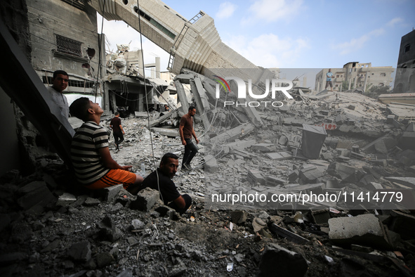 Palestinians are standing on the rubble of Abdullah Azzam Mosque, destroyed in Israeli bombardment in Nuseirat, central Gaza Strip, on July...