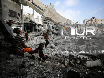 Palestinians are standing on the rubble of Abdullah Azzam Mosque, destroyed in Israeli bombardment in Nuseirat, central Gaza Strip, on July...