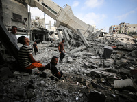 Palestinians are standing on the rubble of Abdullah Azzam Mosque, destroyed in Israeli bombardment in Nuseirat, central Gaza Strip, on July...