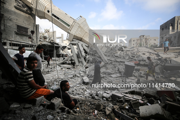 Palestinians are standing on the rubble of Abdullah Azzam Mosque, destroyed in Israeli bombardment in Nuseirat, central Gaza Strip, on July...