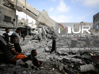 Palestinians are standing on the rubble of Abdullah Azzam Mosque, destroyed in Israeli bombardment in Nuseirat, central Gaza Strip, on July...