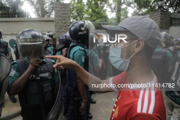 Anti-quota protestors are pointing at a police officer to answer the reason for shooting their fellow protester who died yesterday in Dhaka,...