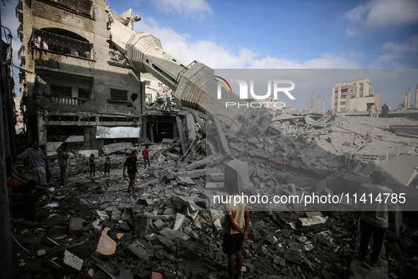 Palestinians are standing on the rubble of Abdullah Azzam Mosque, destroyed in Israeli bombardment in Nuseirat, central Gaza Strip, on July...