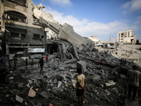 Palestinians are standing on the rubble of Abdullah Azzam Mosque, destroyed in Israeli bombardment in Nuseirat, central Gaza Strip, on July...