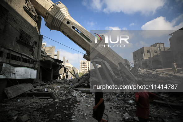 Palestinians are standing on the rubble of Abdullah Azzam Mosque, destroyed in Israeli bombardment in Nuseirat, central Gaza Strip, on July...