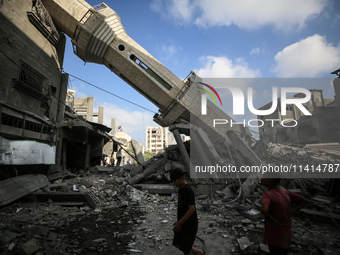 Palestinians are standing on the rubble of Abdullah Azzam Mosque, destroyed in Israeli bombardment in Nuseirat, central Gaza Strip, on July...